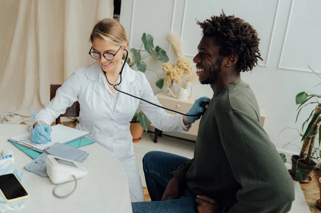 A doctor measures a patient's blood pressure using a sphygmomanometer in a clinical setting.  