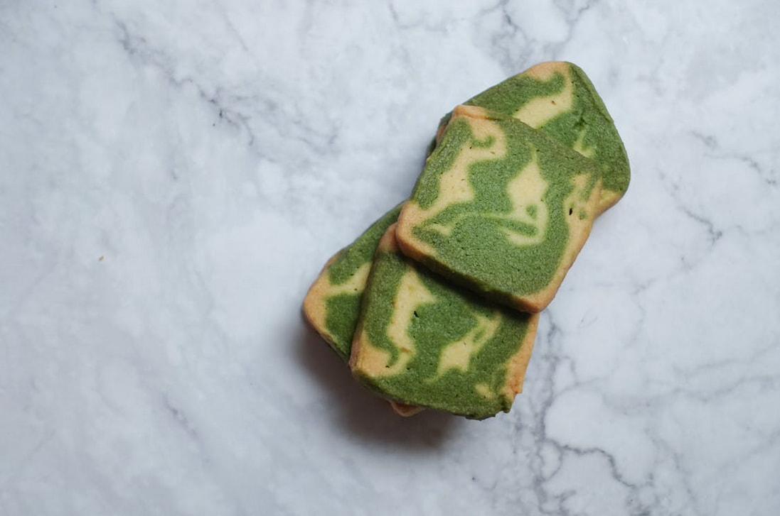 Matcha cookies arranged on a marble countertop, showcasing their vibrant green color and textured surface.  
