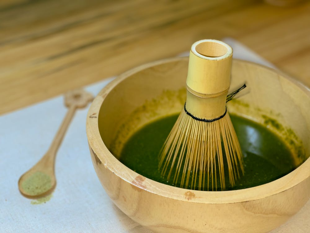 A close-up image of a cup of green tea, emphasizing its warm color and the subtle steam wafting above the liquid.
