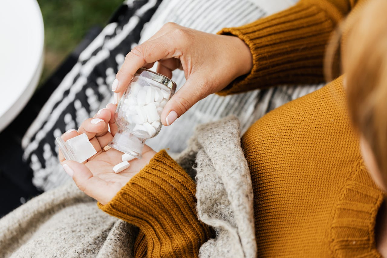 A woman holds a bottle of pills, looking thoughtfully at the container in her hand. 