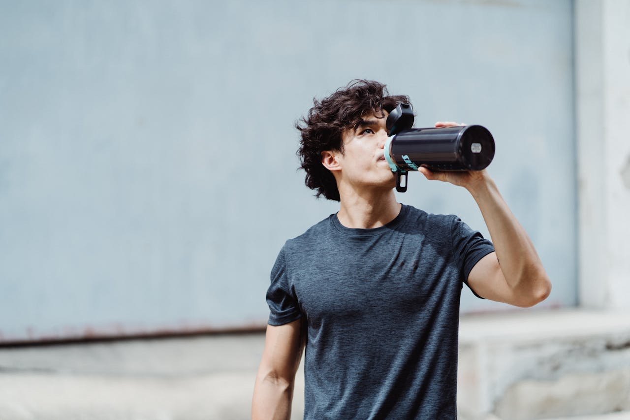 A man takes a sip from a water bottle, showcasing a moment of hydration.