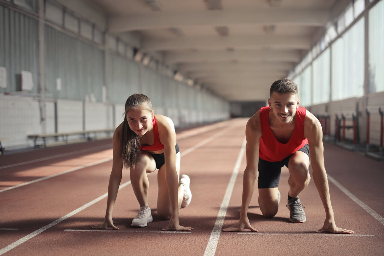 Two individuals running side by side on a track, focused on their exercise routine. 