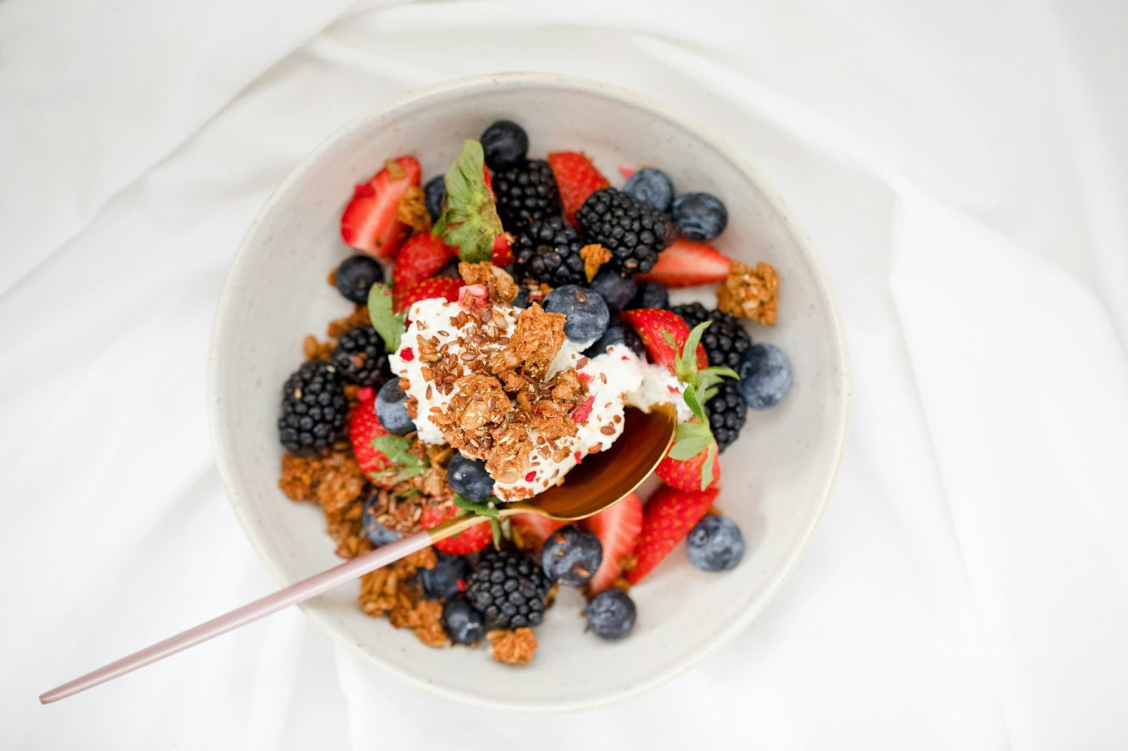 A healthy breakfast bowl filled with granola, fresh berries, and a drizzle of honey, served in a white ceramic bowl.  