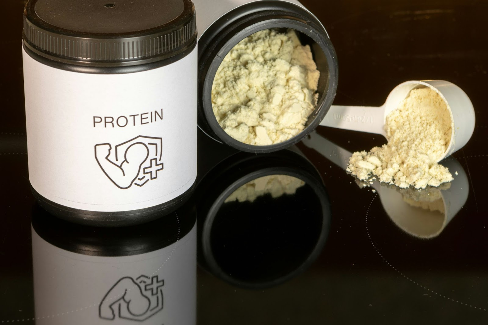 A container of protein powder accompanied by a spoon, set against a neutral background.