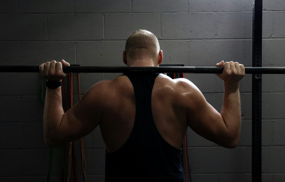 A man performs pull-ups on a bar in a gym, showcasing strength and fitness. 
