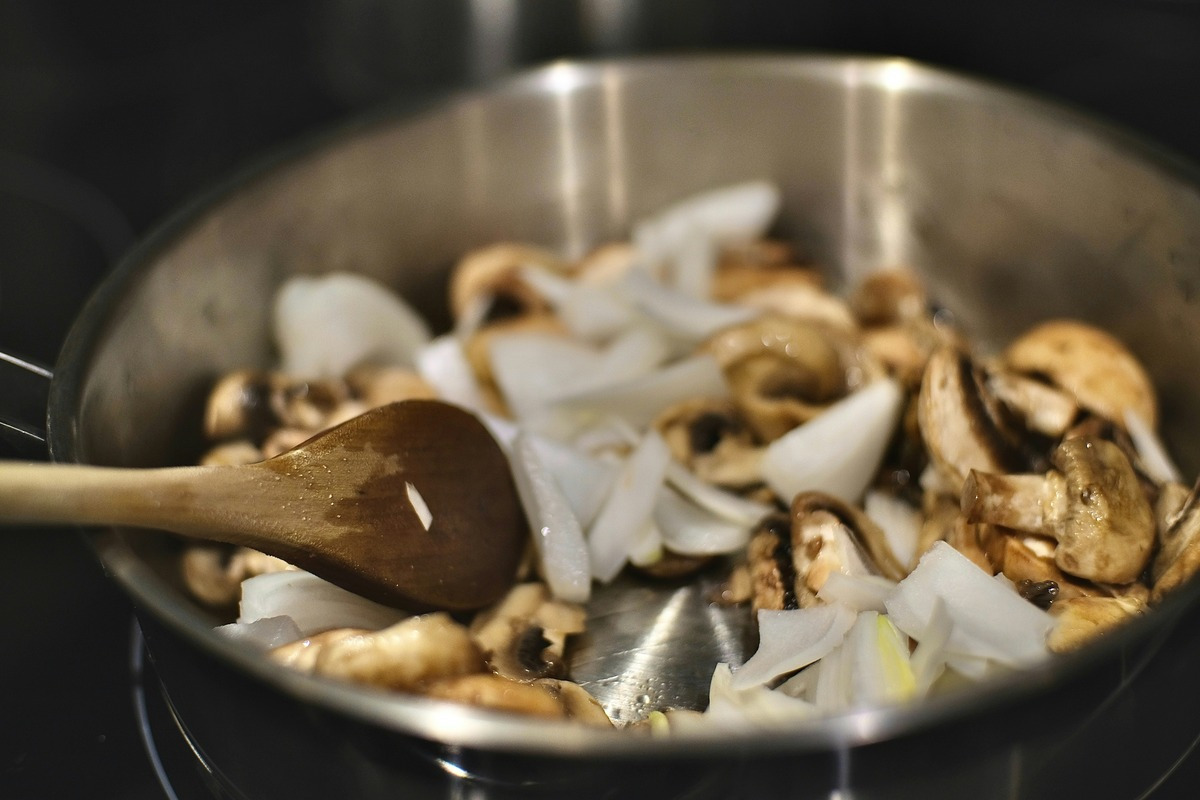 A frying pan filled with sautéed mushrooms and onions, showcasing a golden-brown color and a savory aroma.  