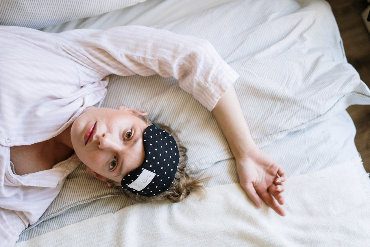 A woman lying in bed, wearing a headband, appears relaxed and comfortable. 