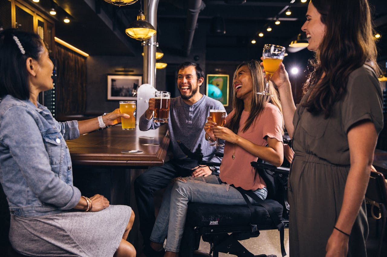 A group of people enjoying drinks while seated at a bar, engaged in conversation and laughter.  