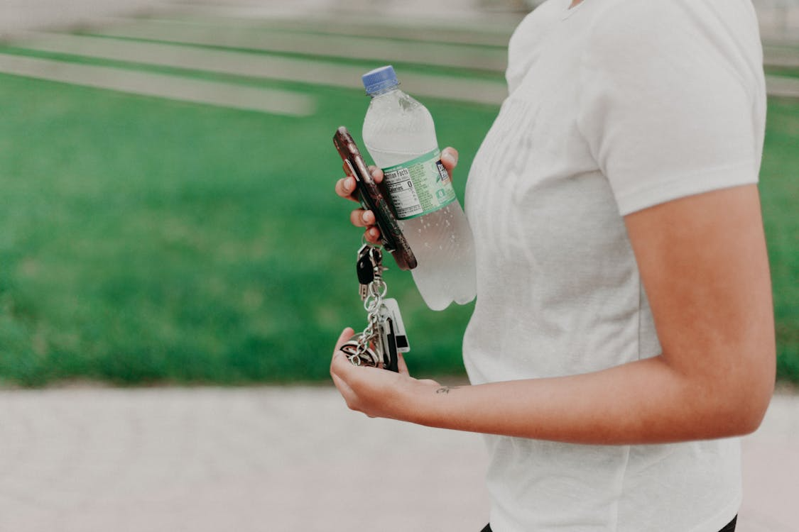 A woman holds a bottle of water in one hand and a keychain in the other, smiling at the camera.