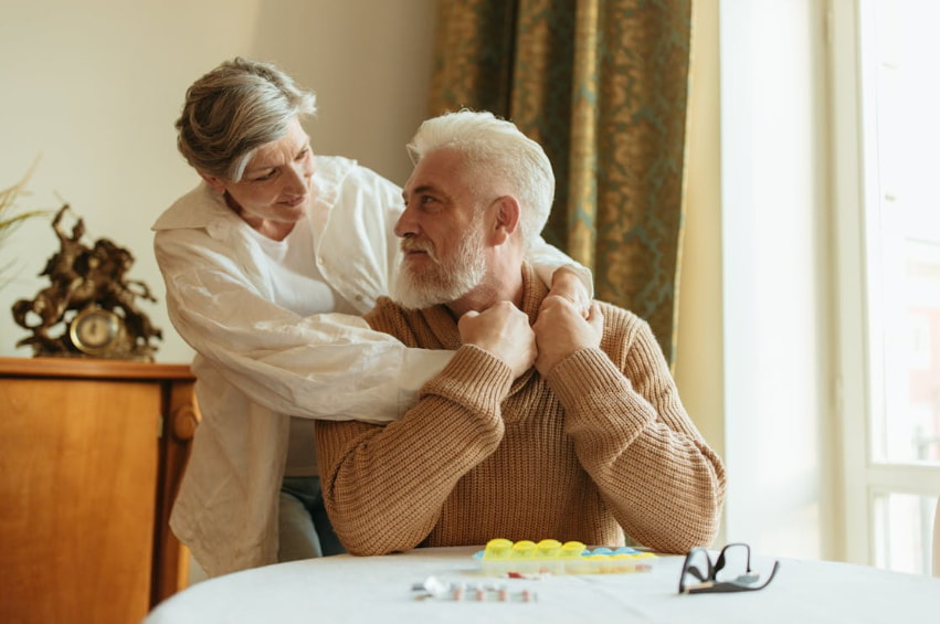 Senior couple sitting together in a cozy living room, smiling and enjoying each other's company.  