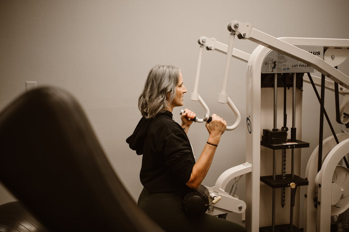 A woman exercises on a gym machine, focusing on her workout in a well-equipped fitness center.  