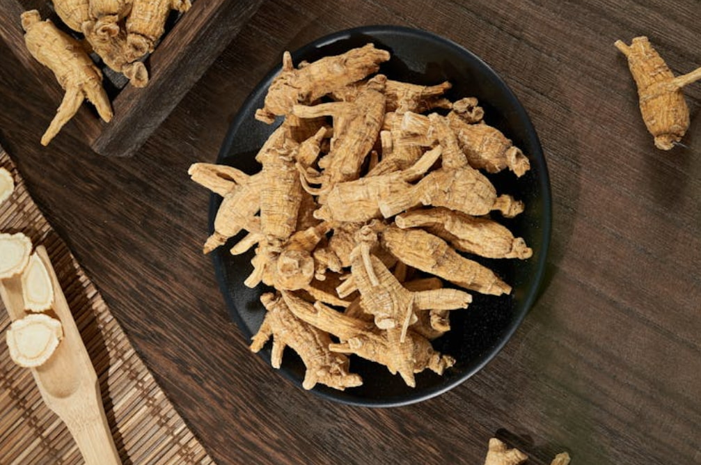 A close-up view of dried ginseng displayed on a white plate atop a rustic table.