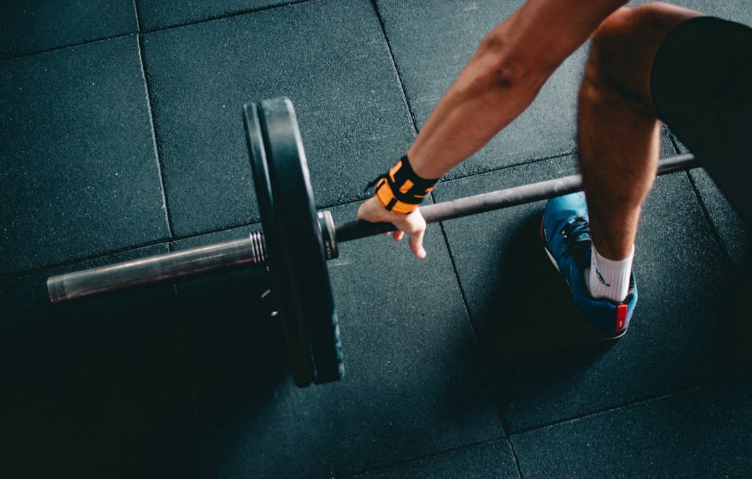 A person lifts a barbell on a gym floor, demonstrating strength training and fitness activity. 