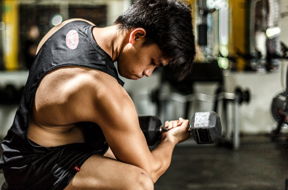A man squats while holding a dumbbell, focusing on strength training in a gym setting. 