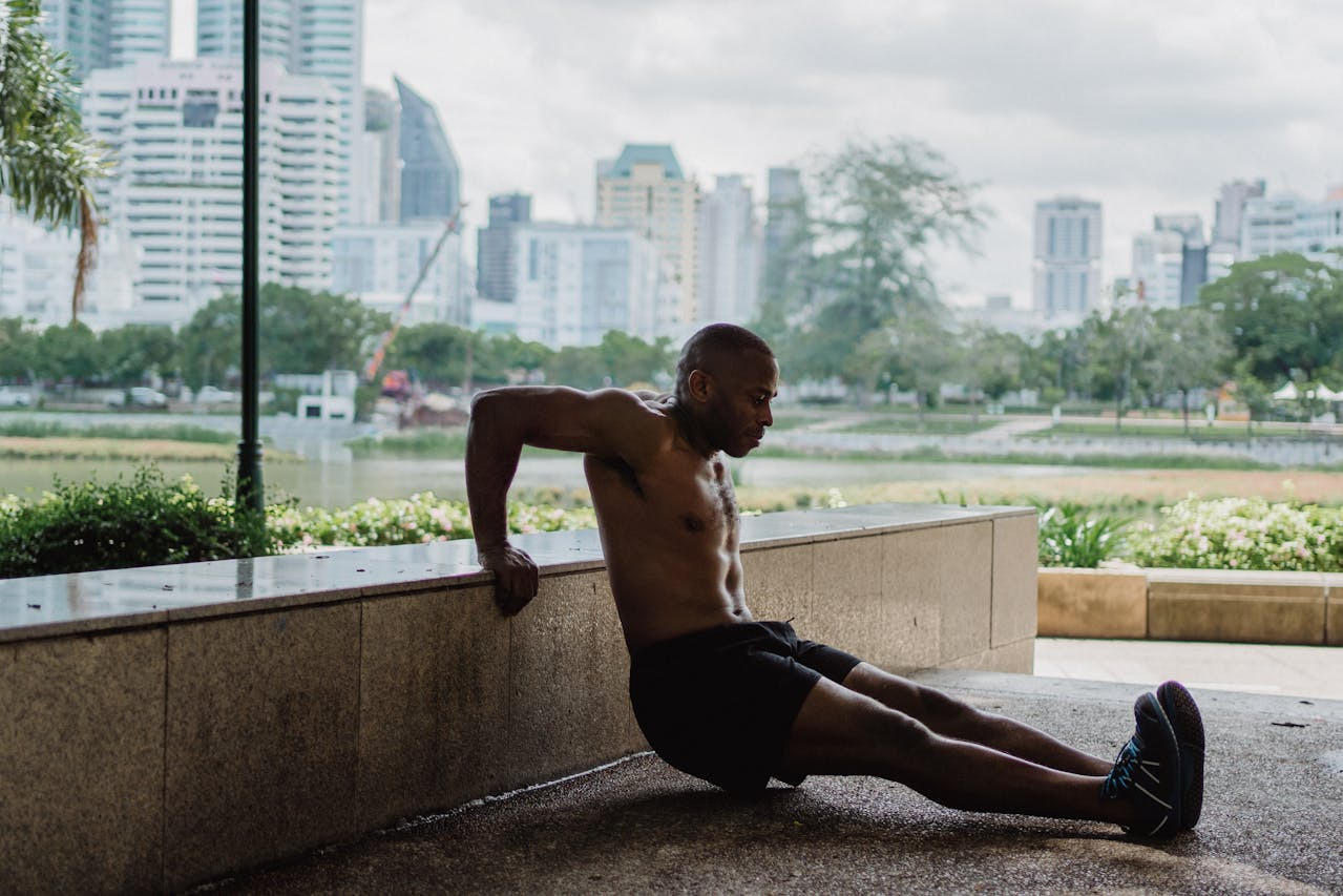 A man performs push-ups against a concrete wall, showcasing strength and fitness in an outdoor setting.  