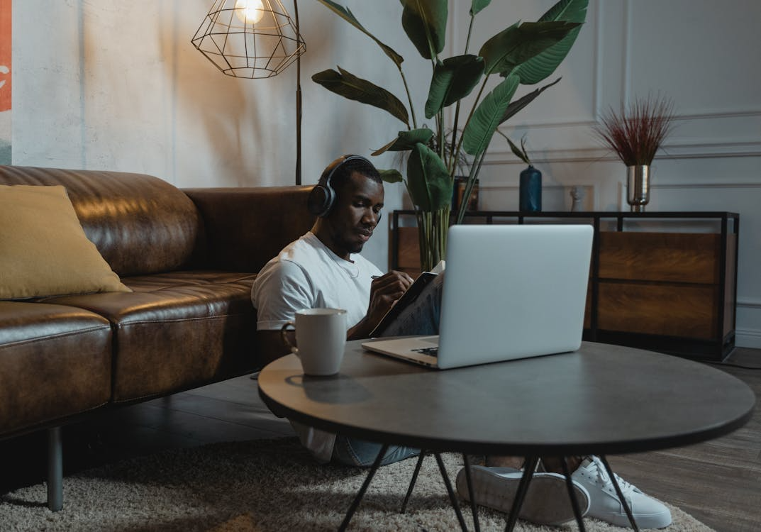 man reading and drinking coffee by his open laptop