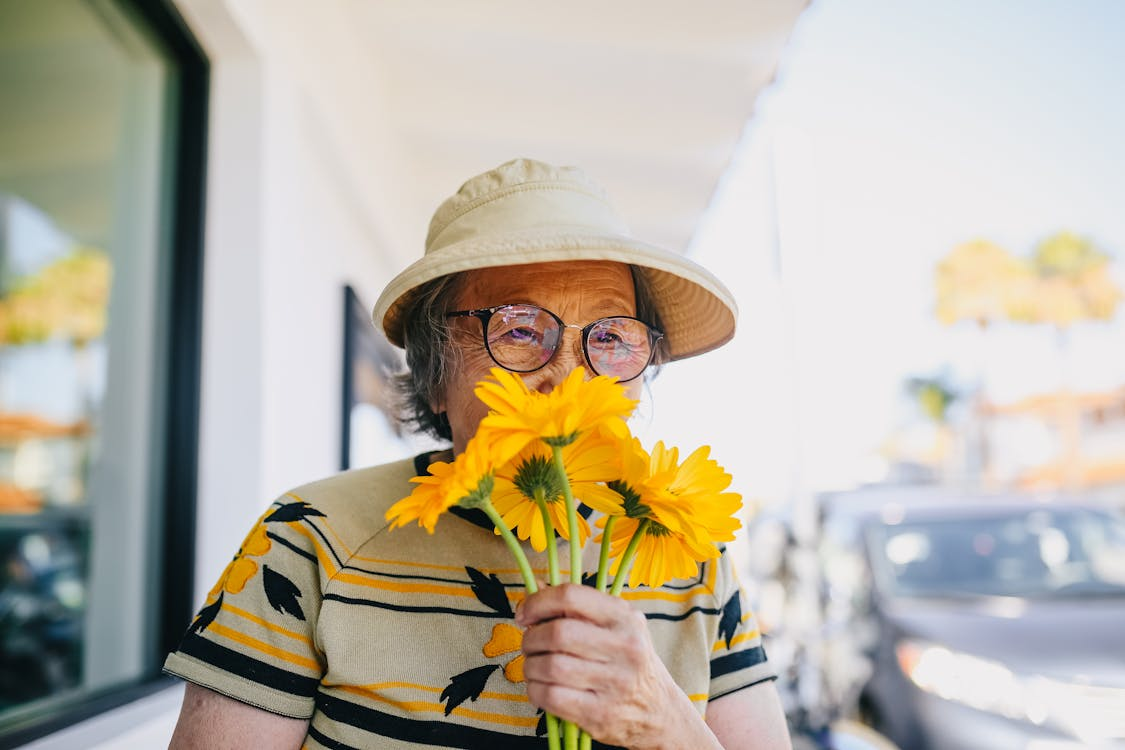 older woman stopping to smell the flowers