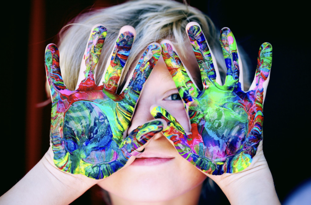 child with colorful paint on their hands