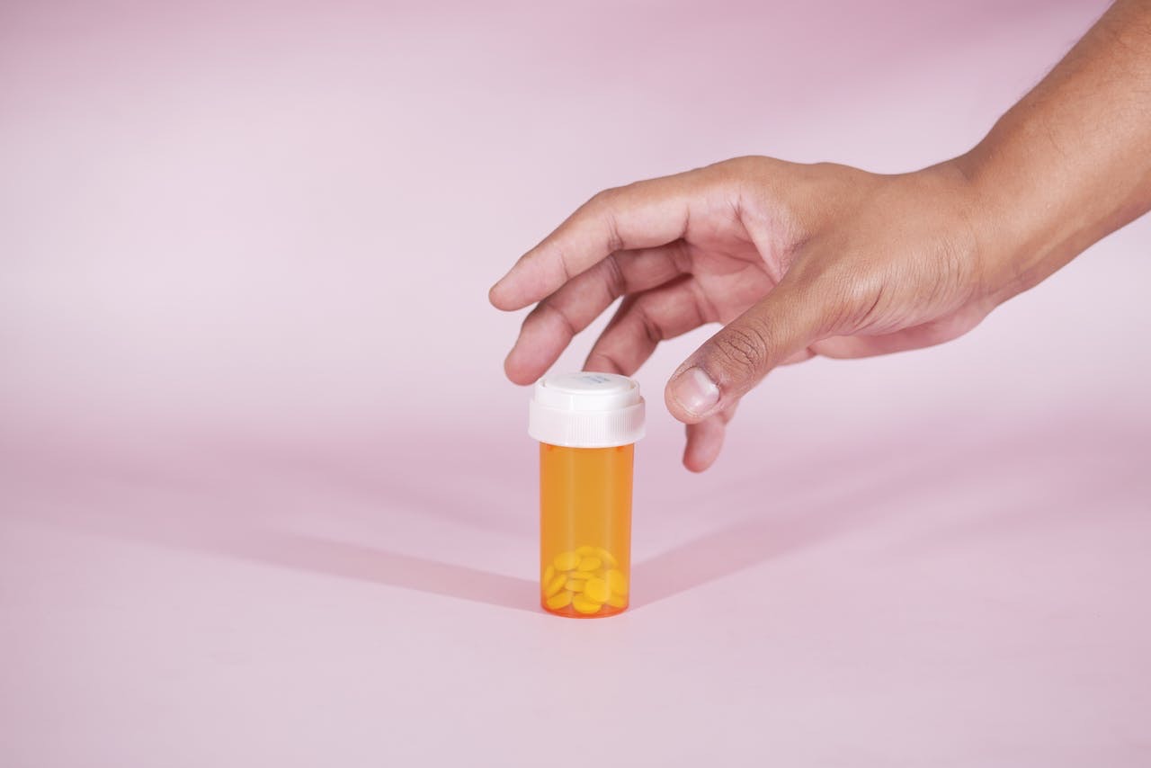 person reaching for an orang prescription bottle