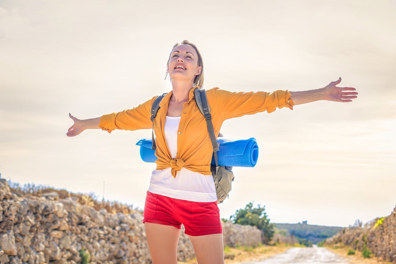 woman on a hiking path with her arms outstretched looking happy and serene