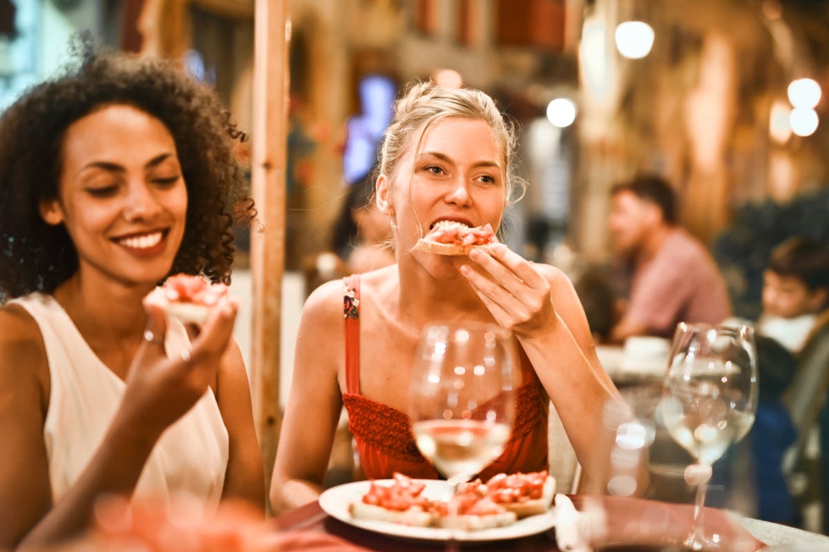 two women eating bruschetta at a restaurant