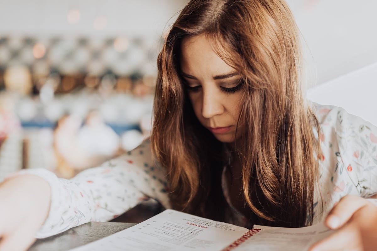woman bent over a book with a look of concentration on her face as she reads
