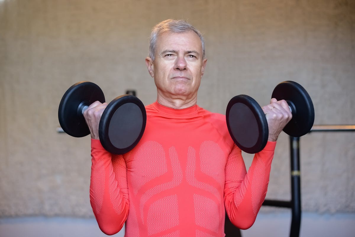 man with gray hair performing dumbell curls