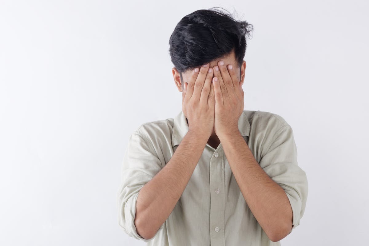 man covering his face with his hands