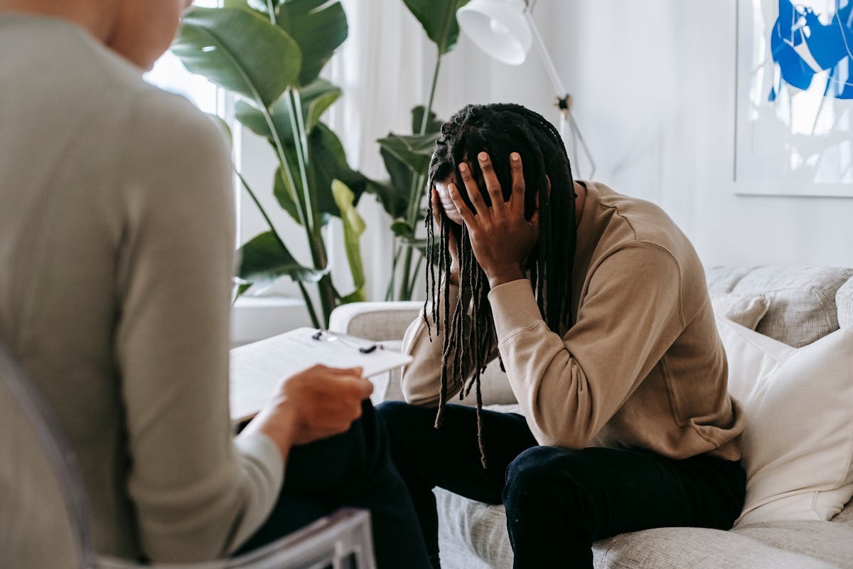 man with dreadlocks sitting in a therapist's office, his head in his hands as he talks about his anxiety