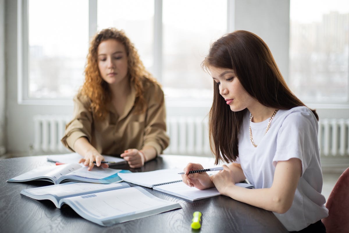 woman sitting at a table getting tutored as she focuses on schoolwork