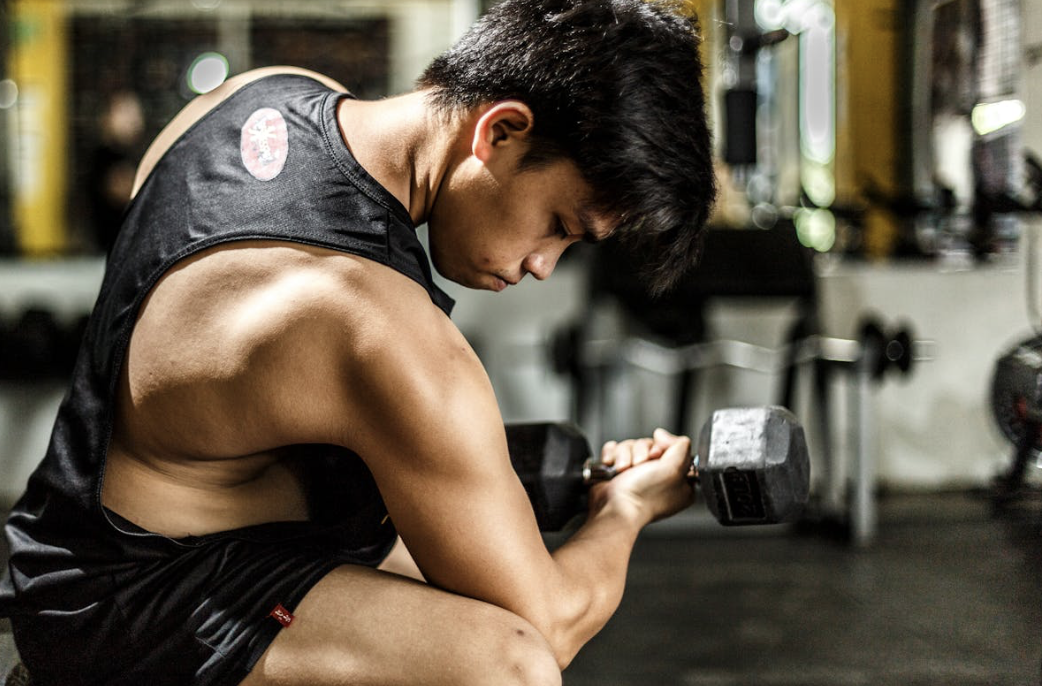 man performing a bicep curl, looking at his arm and wondering if collagen helps with muscle growth