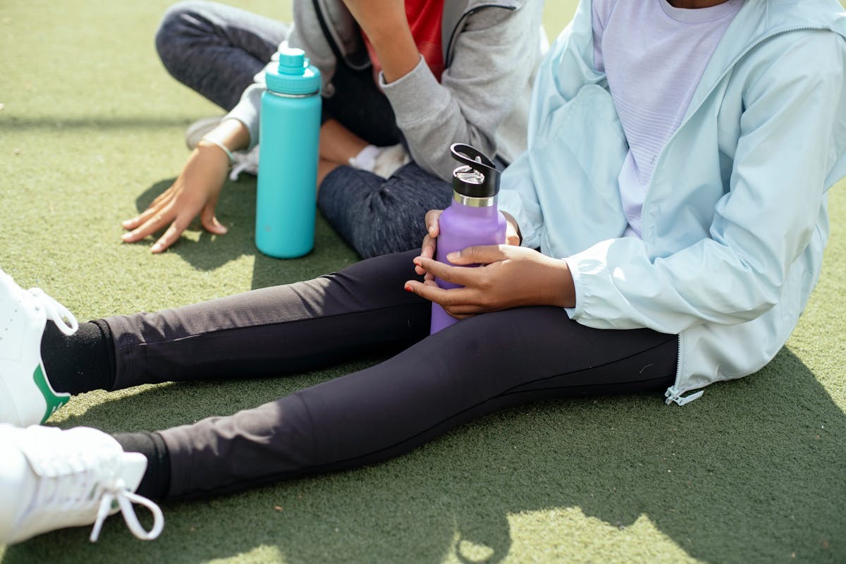 women taking a break from their regular workout routine to rest and sip some water before the next set