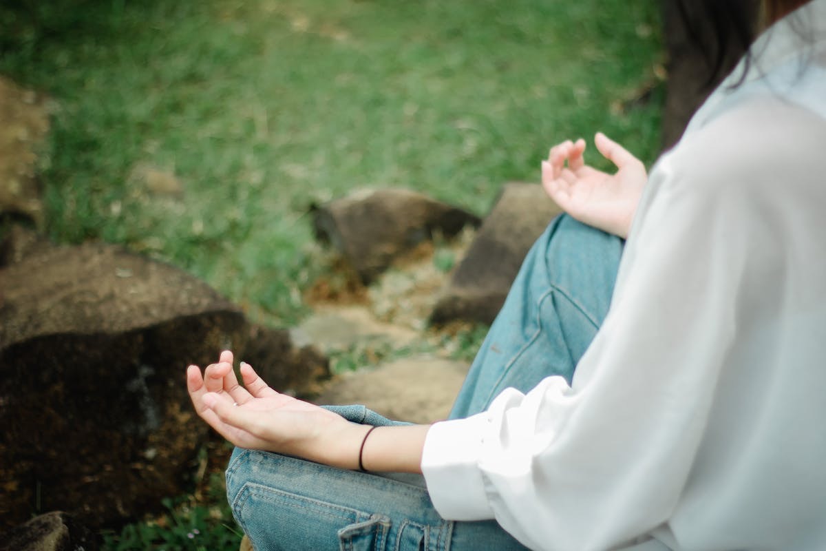 woman seated in the forest, meditating to reduce stress