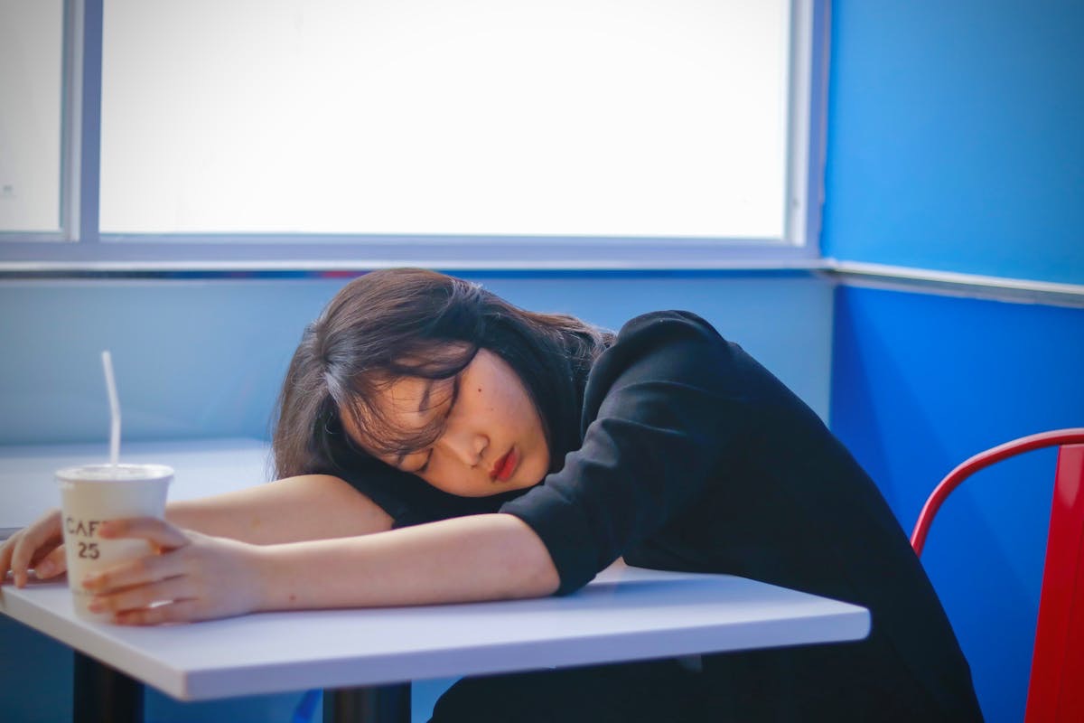 woman taking a nap on the table at a fast food restaurant because she is exhausted
