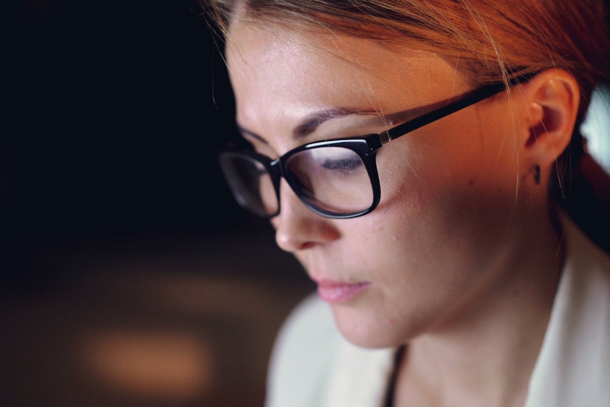 woman wearing glasses focusing intently on work