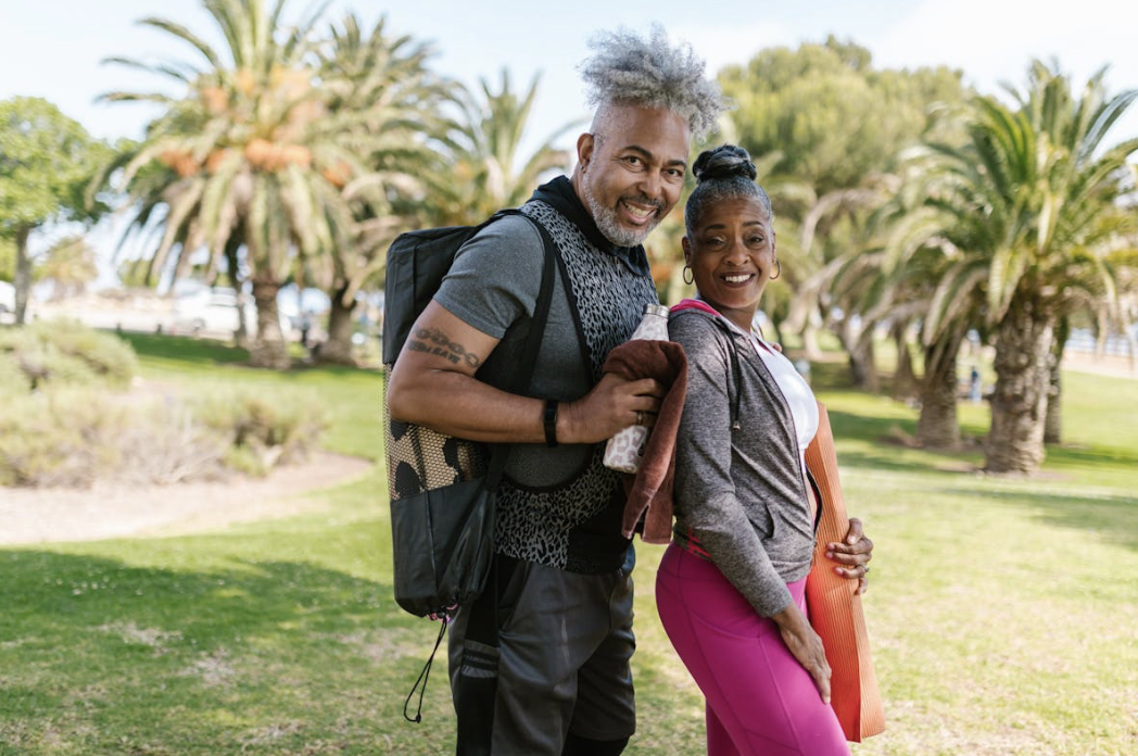 healthy older couple posing together in athleticwear on their way to an outdoor yoga class