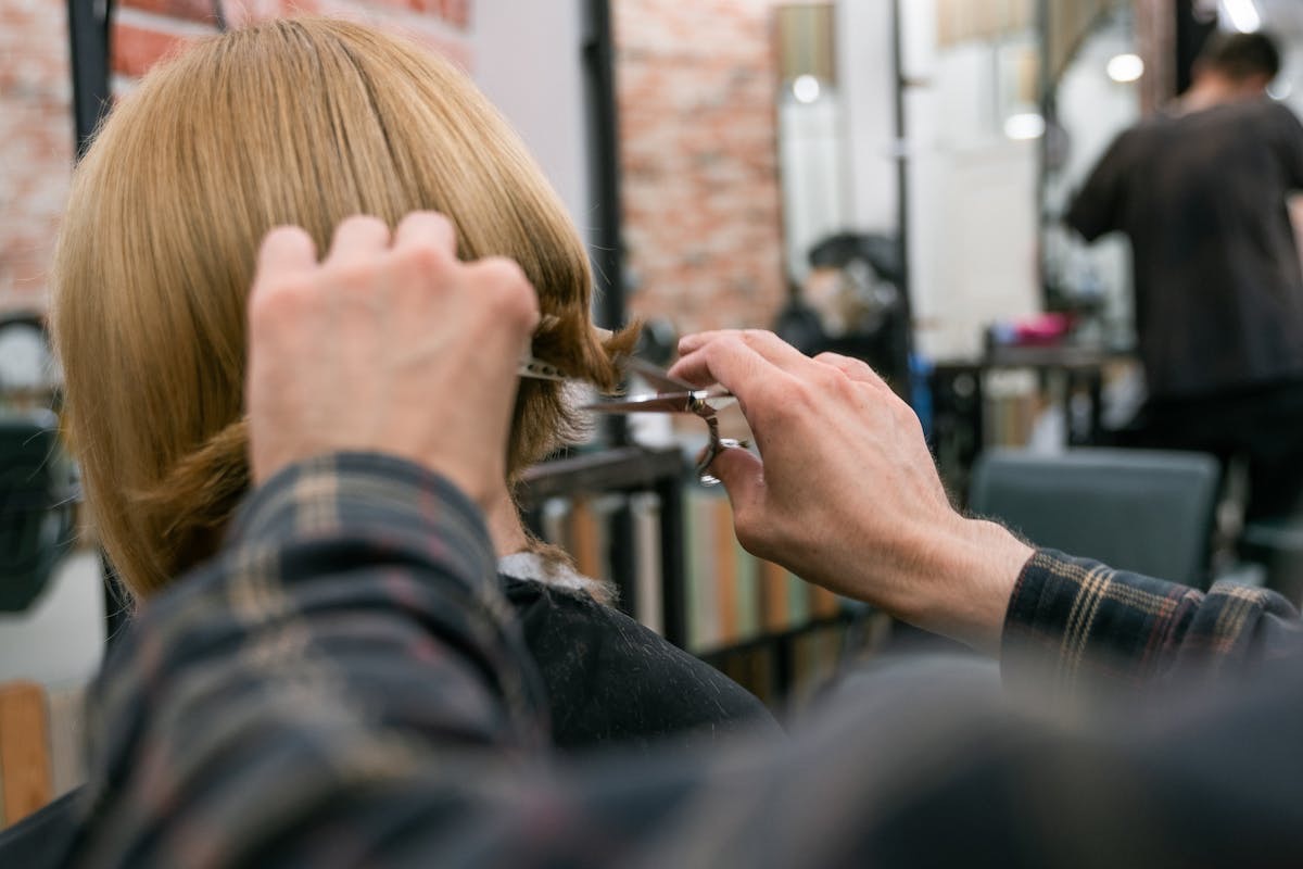 woman with blonde hair getting a bob haircut at the salon