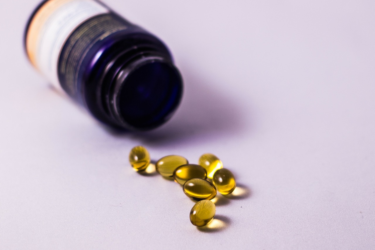 A bottle is tipped on its side, coming out of it are several supplements.