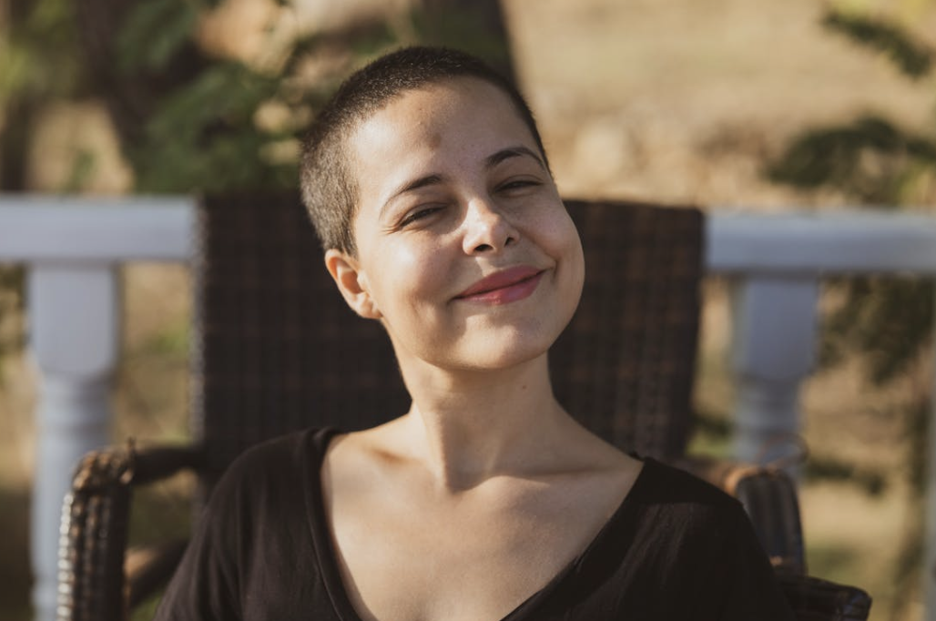 happy woman with short hair standing outside on a sunny day with a soft smile on her face