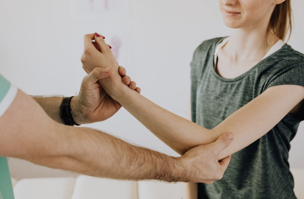 doctor examining a woman's elbow joint for inflammation