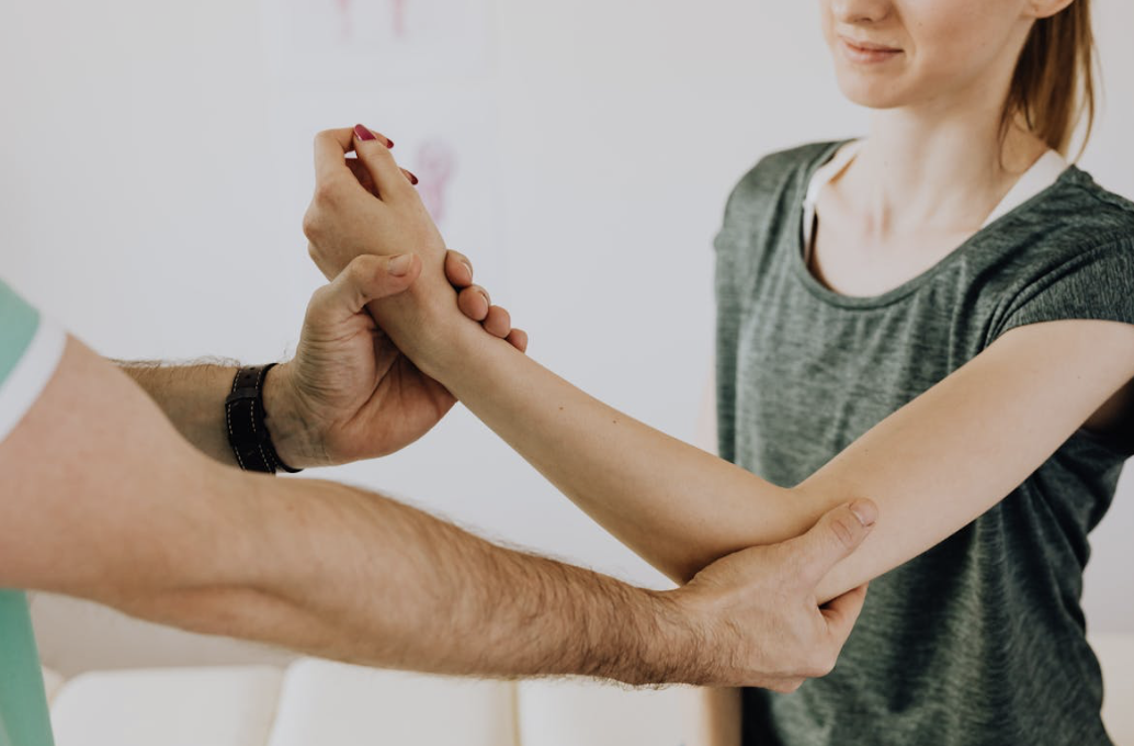 doctor examining a woman's elbow joint for inflammation