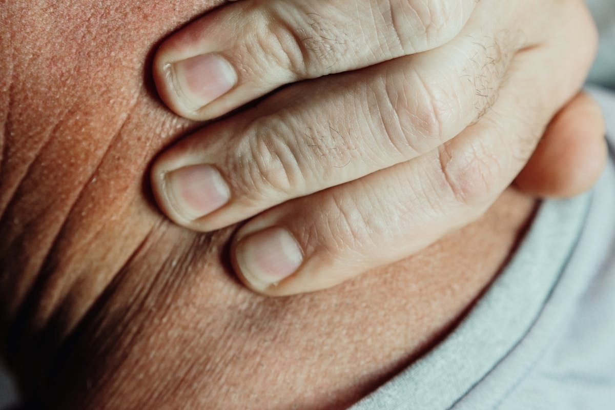 man kneading his neck with his fingers to relieve stiffness and pain
