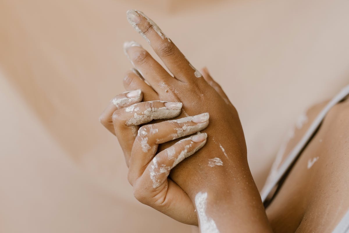 woman with clay dried to her hands to give the idea of uncomfortably dry, flaky skin 