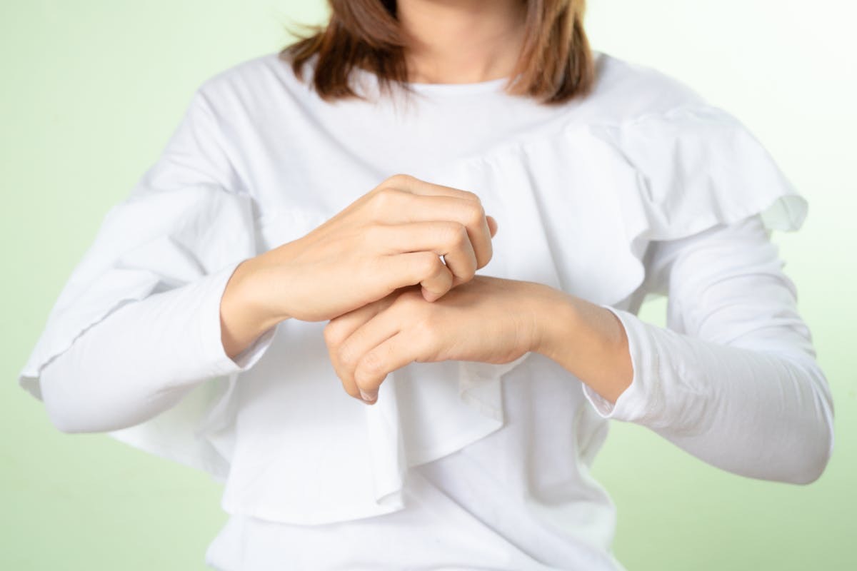 woman scratching the skin on the backs of her hands