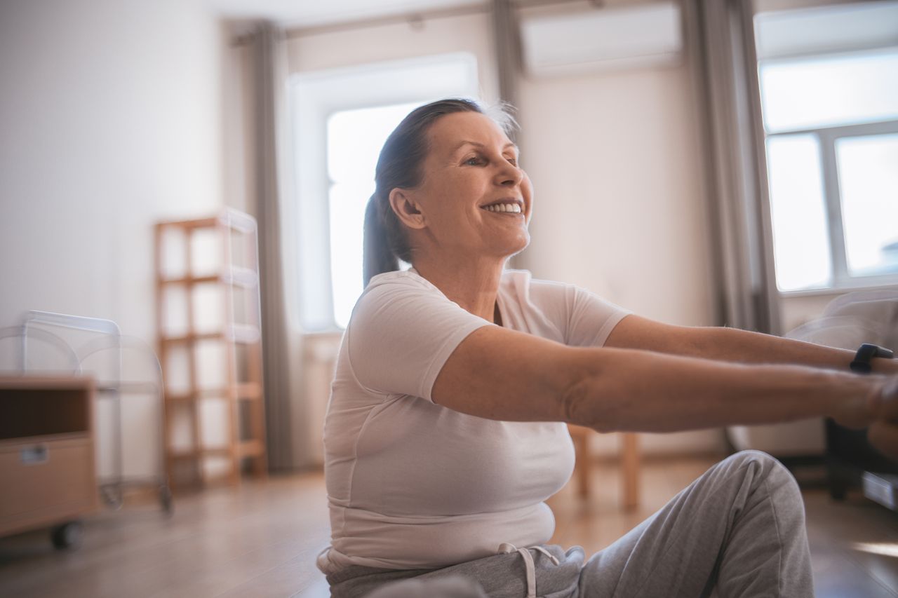 healthy middle aged woman smiling as she stretches for yoga class