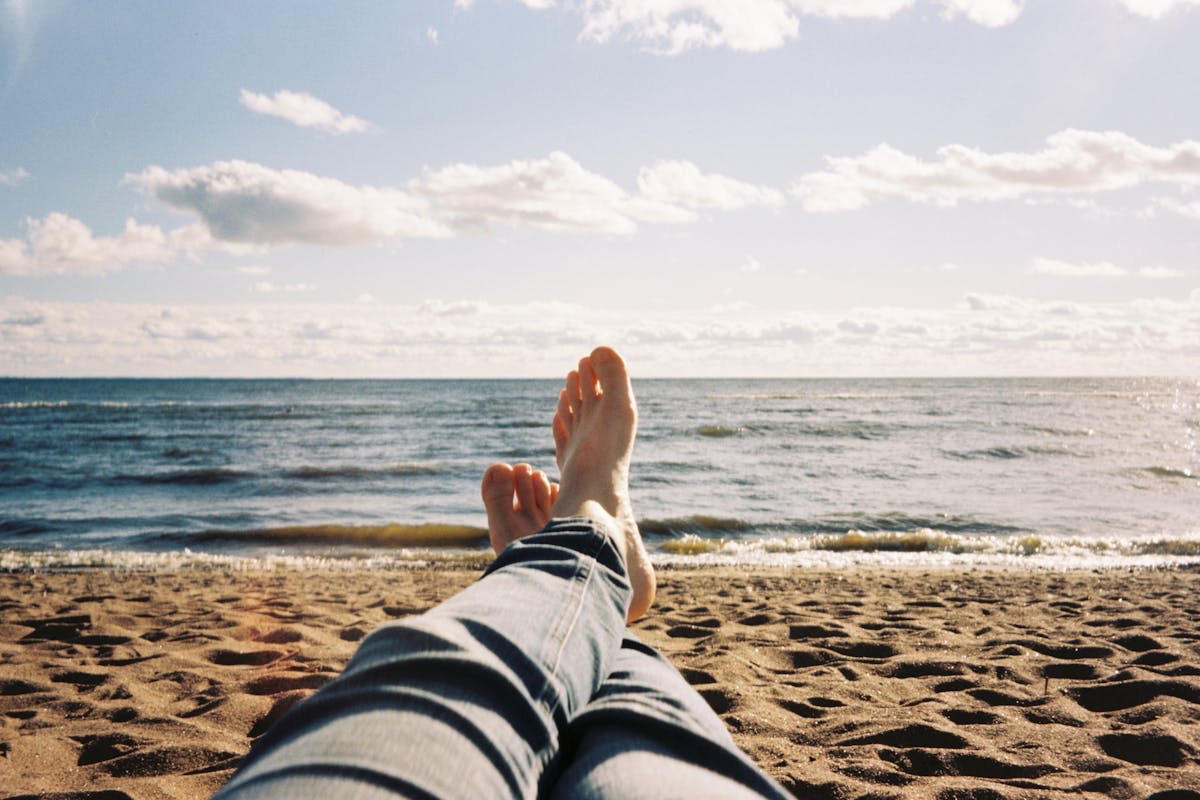 feet crossed as a person lies on a beach