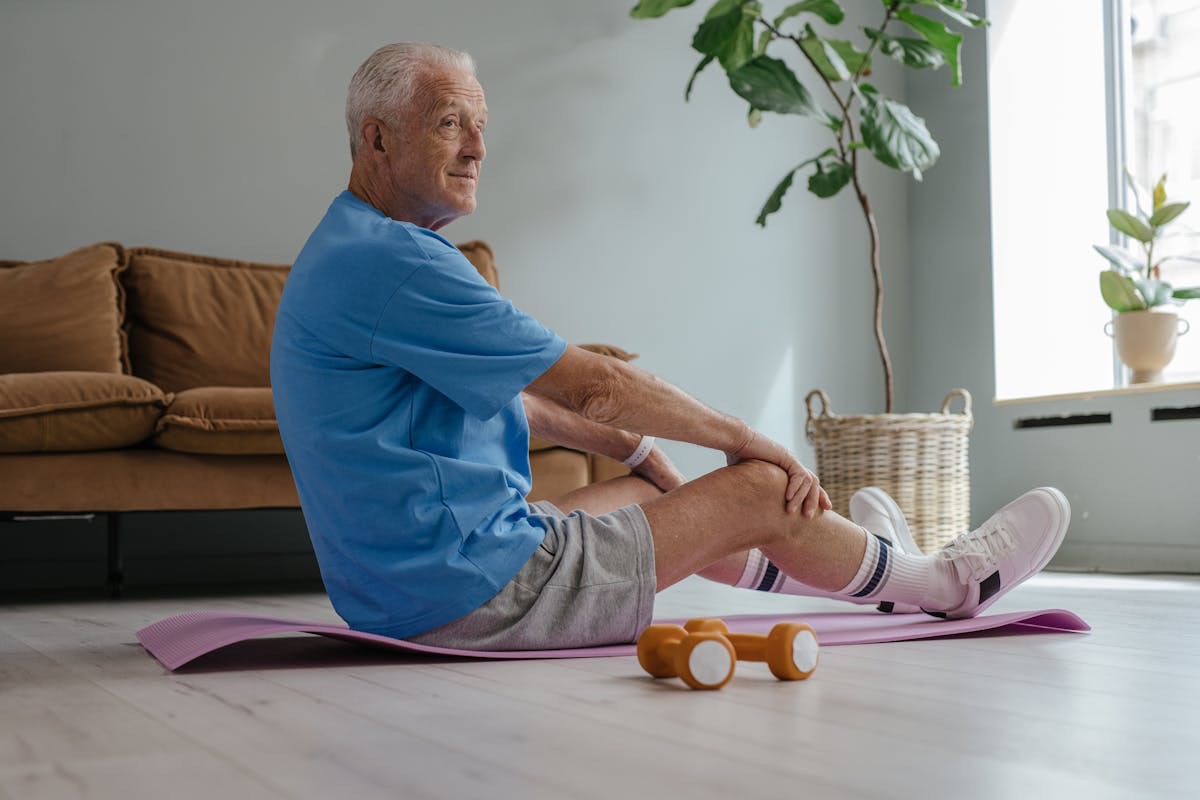 older man sitting on the floor stretching before a workout