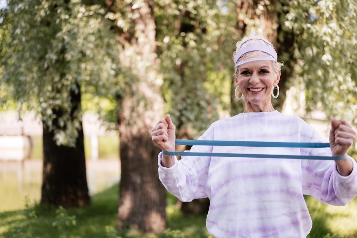 older woman in purple workout gear using a resistance band to do an arm exercise
