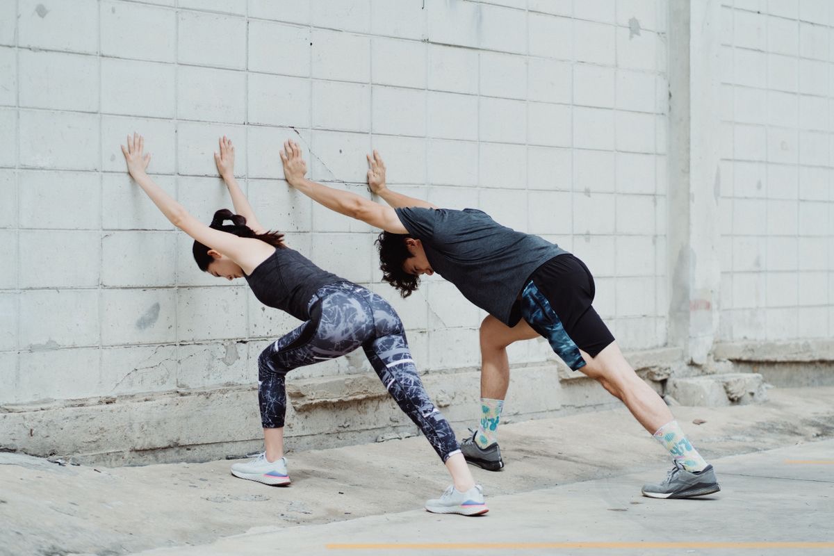 two runners stretching against a wall 