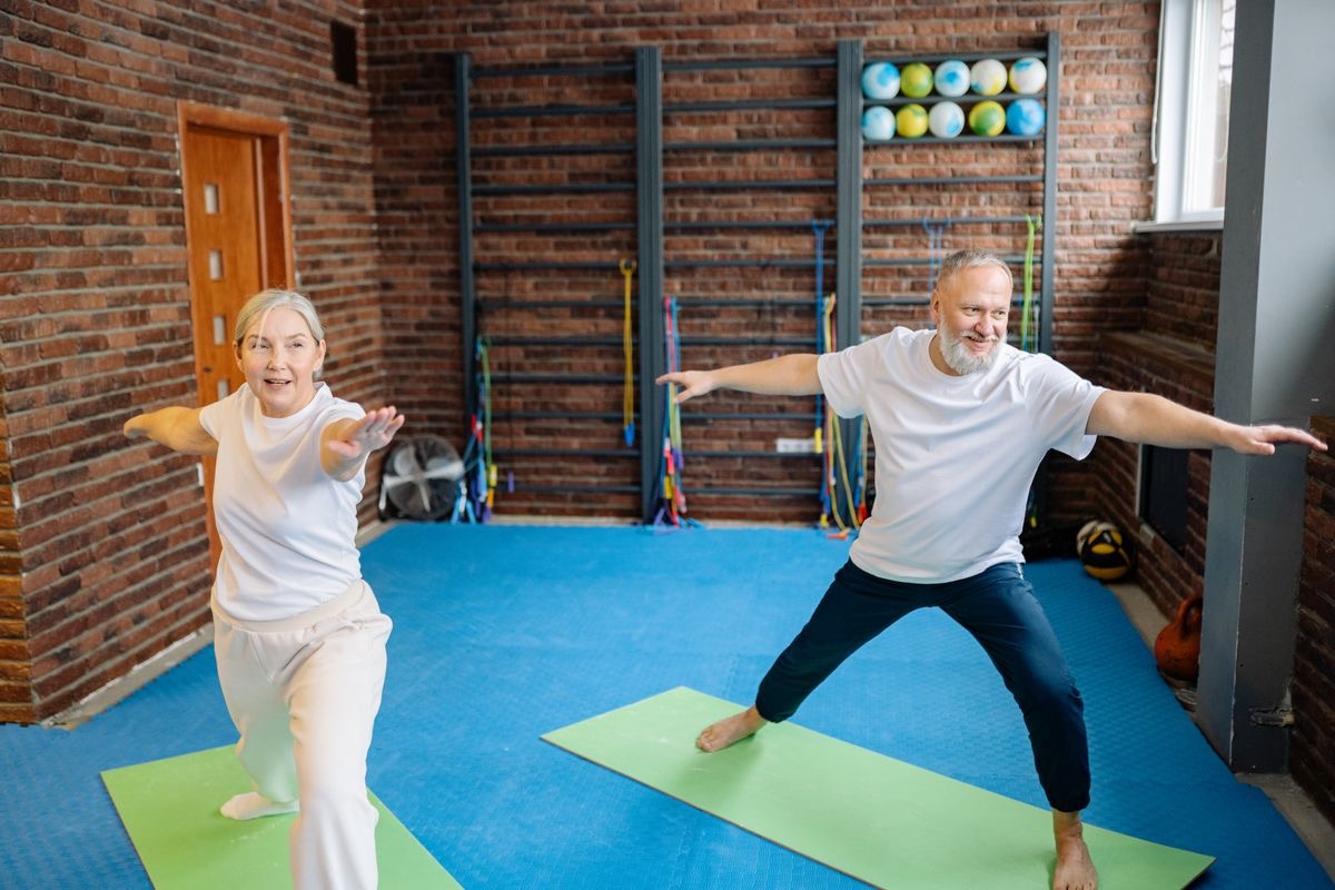 two older people in an exercise studio doing warrior pose